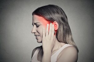 A woman holding her ear in pain