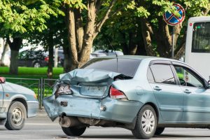 A blue car has the back fender and trunk collapsed after crashing