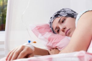 A thyroid cancer patient lies on their side in a hospital bed.