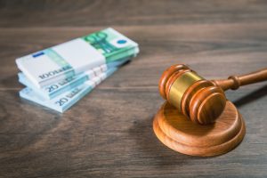A pile of money notes and a gavel on an oak table to represent farm accident compensation.