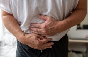 A man in discomfort holding his stomach.