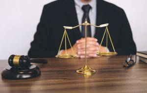 A No Win no Fee blood clot claims solicitor sits behind a desk with a gavel and scales