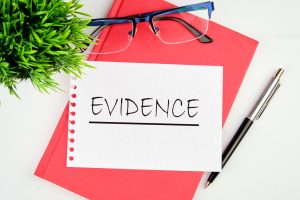 A red evidence book, containing medical evidence, on a table with glasses. 