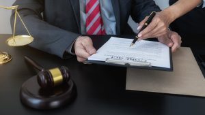 Person signing contract alongside personal injury lawyer.