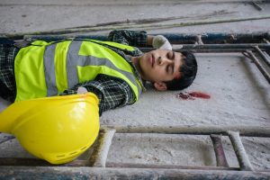A builder on the floor after falling from a height. He is bleeding from the head. 