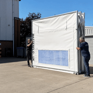 Two fitters folding a ROLARE-FLEX + MOBE-X enclosure outdoors